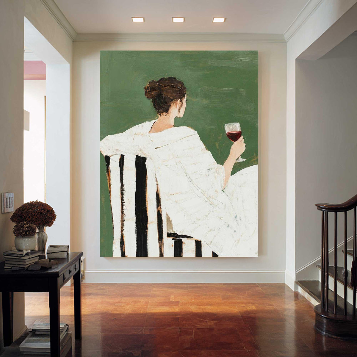 May include: An abstract painting depicts a person in a white robe seated in a black and white striped chair, holding a glass of red wine. The background is a solid green color. The artwork is displayed in a well-lit hallway with a dark wood floor.