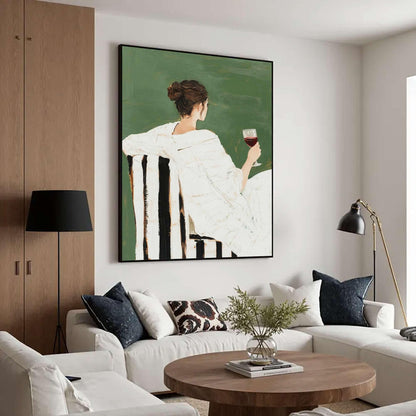 May include: An abstract painting depicts a person in a white robe holding a glass of red wine, seated in a black and white striped chair. The background is a solid green color. The artwork is framed in black and hangs on a white wall.