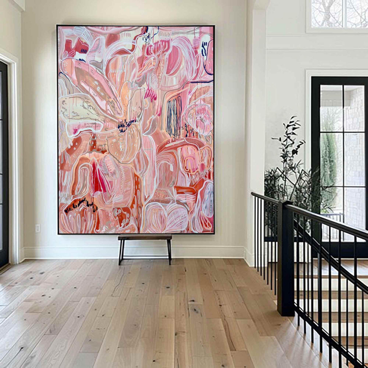 May include: Large abstract painting with a black frame. The artwork features a complex composition of pink, peach, and white brushstrokes. The painting is displayed in a bright, modern entryway with hardwood floors.