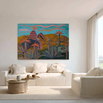 May include: An original painting depicts a figure on horseback in a desert landscape. The artwork features a blue sky, yellow mountains, and cacti. The rider wears a striped shirt and hat. The painting is displayed above a white sofa.