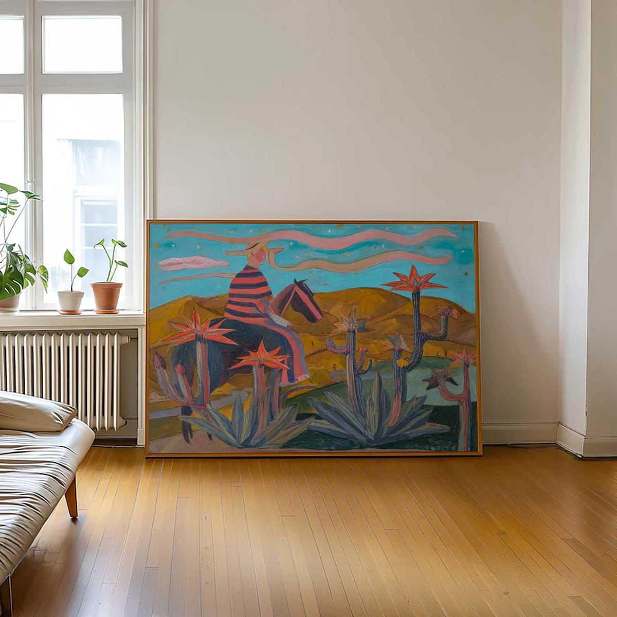 May include: Large framed painting depicting a cowboy on horseback in a desert landscape. The artwork features a color palette of blues, oranges, and pinks, with cacti and a starry sky. The cowboy wears a striped shirt and hat.