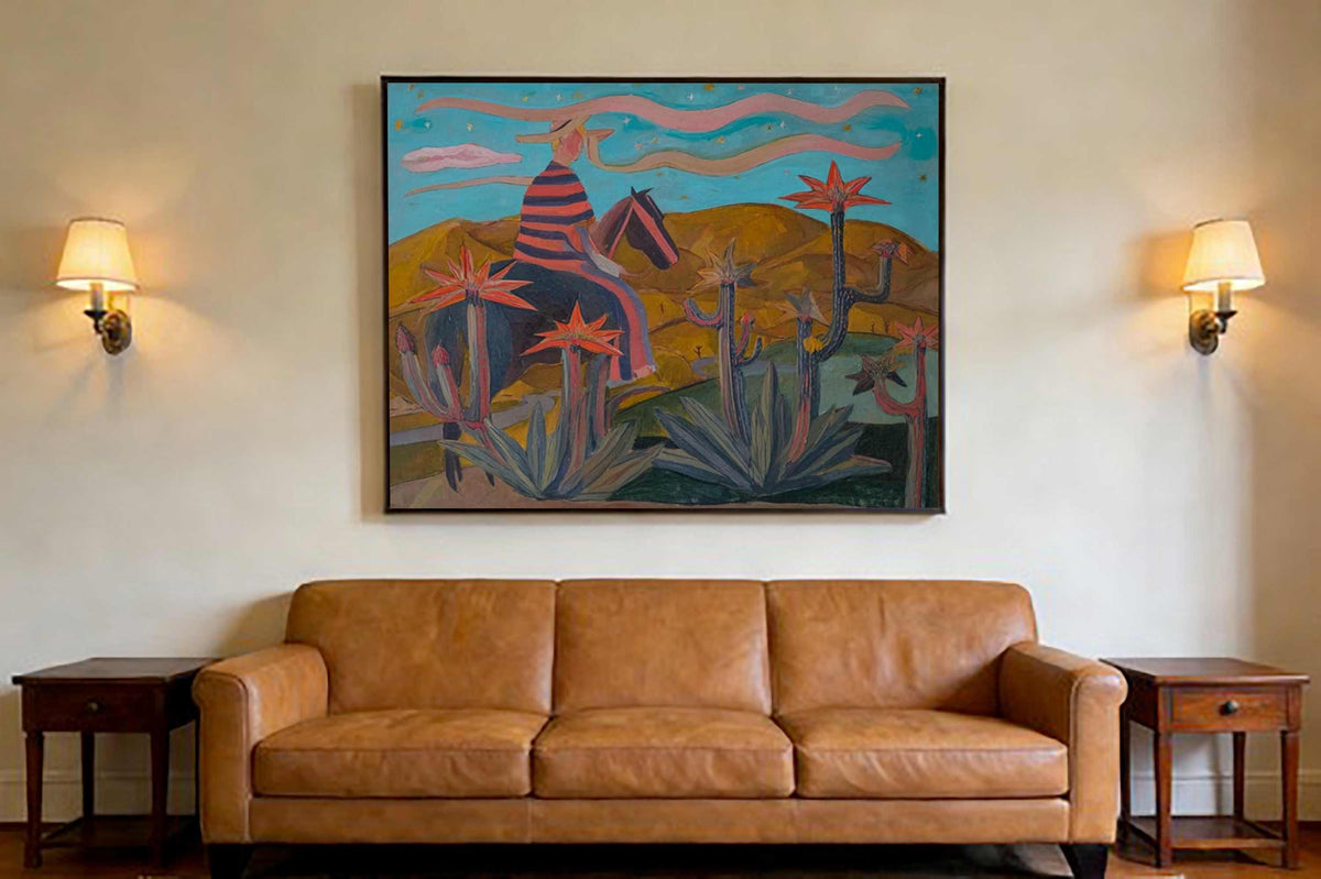 May include: A large framed painting depicting a figure on horseback in a desert landscape, above a brown leather sofa. The painting features a rider in a striped shirt and a horse, with cacti and mountains in the background. Two wall sconces flank the painting.