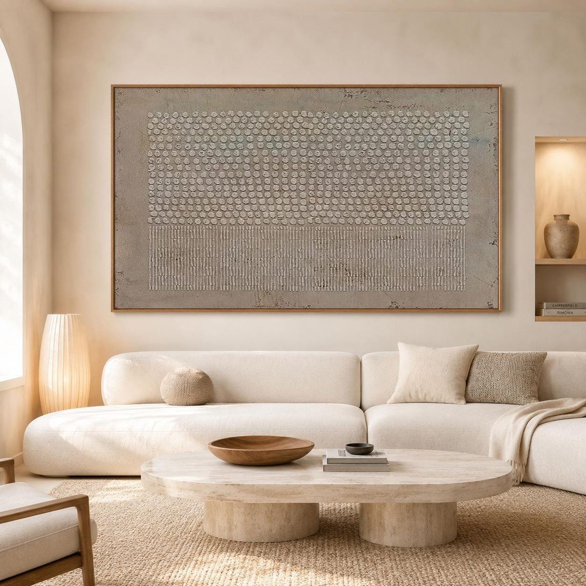 May include: A large rectangular wall art piece featuring a textured beige and cream surface with a top section of raised circular dots and a bottom section of vertical lines, framed in a thin wooden border, displayed above a white sofa.