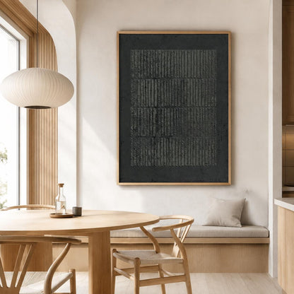 May include: A framed abstract artwork with a dark gray textured surface and vertical lines. The artwork is displayed in a light wood frame. The image also shows a round wooden dining table, chairs, and a pendant light.