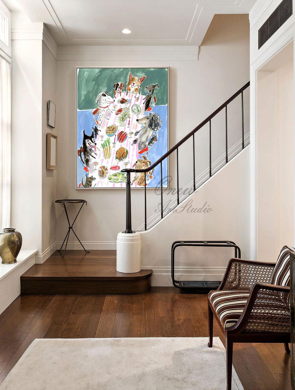 May include: An original painting depicts a whimsical scene of dogs gathered around a table laden with food. The artwork features a green and blue background, with various dog breeds enjoying a meal. The painting is framed and displayed in a well-lit hallway.