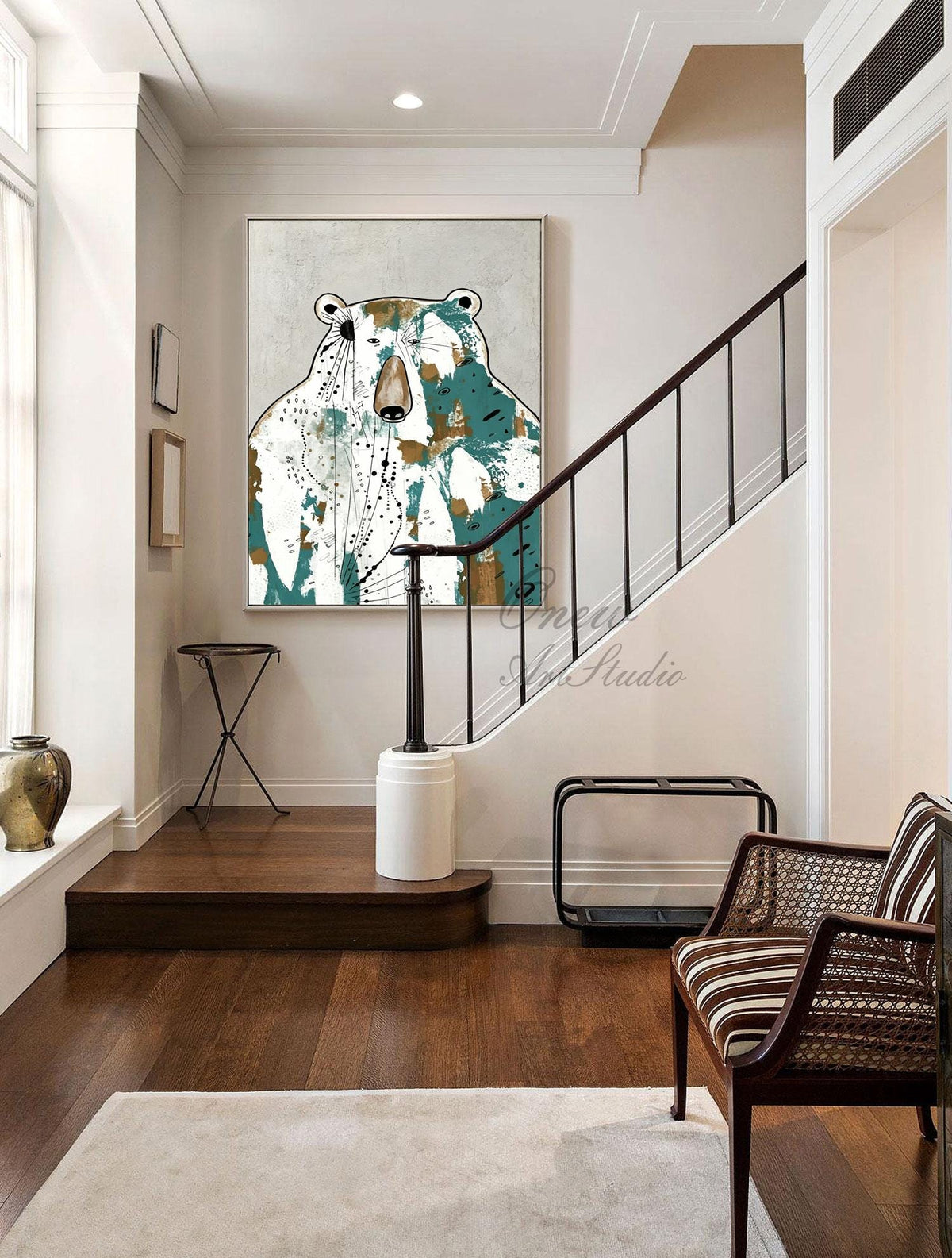 May include: A large framed abstract painting of a bear in a hallway. The bear is depicted with white, teal, and gold brushstrokes. The hallway has a staircase with a dark wood banister and a chair with a striped seat.