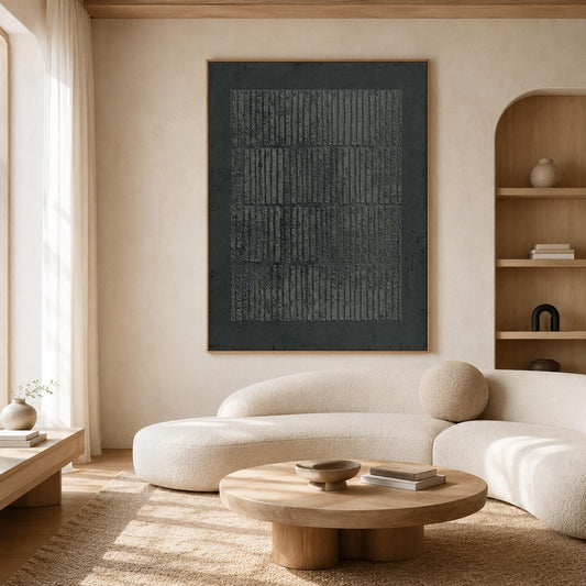 May include: A large, framed abstract artwork with a dark gray textured surface and vertical lines. The artwork hangs above a curved, cream-colored sofa in a modern living room setting. A round wooden coffee table and a beige rug complete the scene.