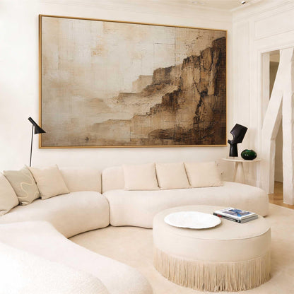 May include: A large rectangular wall art piece featuring an abstract landscape in shades of beige, cream, and dark brown. The painting displays textured, layered brushstrokes that suggest a rocky cliffside or canyon, framed in a thin gold border.