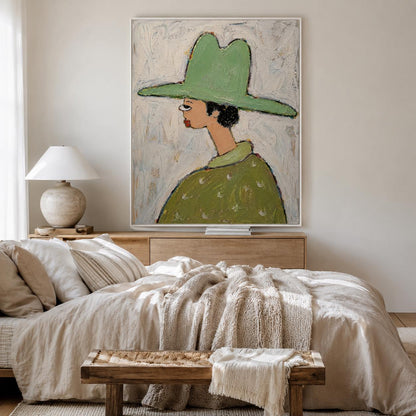 May include: A framed wall art print featuring a stylized portrait of a figure in profile wearing a wide-brimmed light green hat and a matching green shirt with a subtle white pattern, set against a textured, off-white, and light gray background.