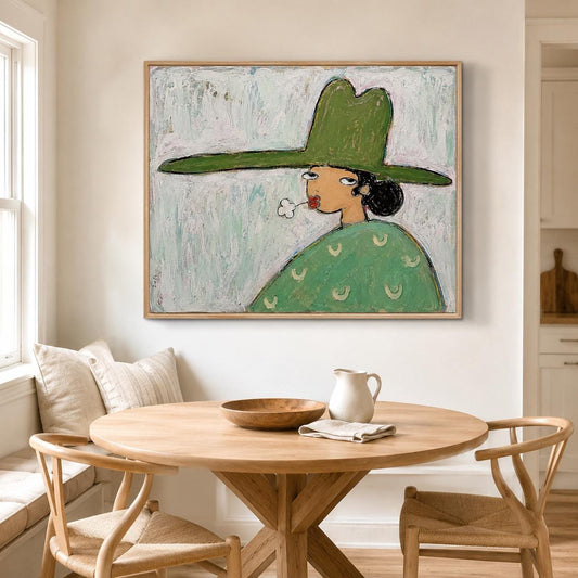 May include: A square framed painting depicting a stylized figure wearing a wide-brimmed green hat and a green patterned shirt. The figure has dark hair, is blowing a small red flower, and is set against a textured, light blue-grey background.