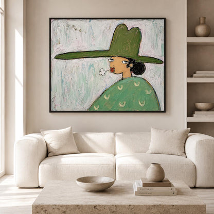 May include: A framed painting featuring a stylized figure wearing a wide-brimmed green hat and a matching green garment with small crescent patterns. The figure has dark hair, red lips, and is blowing a small white cloud against a light blue background.