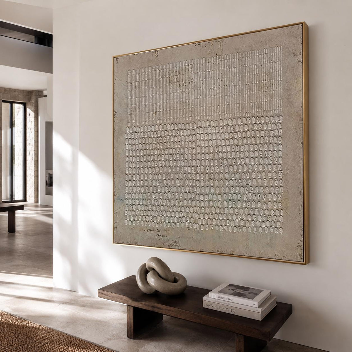 May include: A large square wall art piece featuring a textured beige and off-white surface with a geometric pattern of vertical lines on the top half and a grid of small raised circular shapes on the bottom half, framed in a thin gold metal frame.