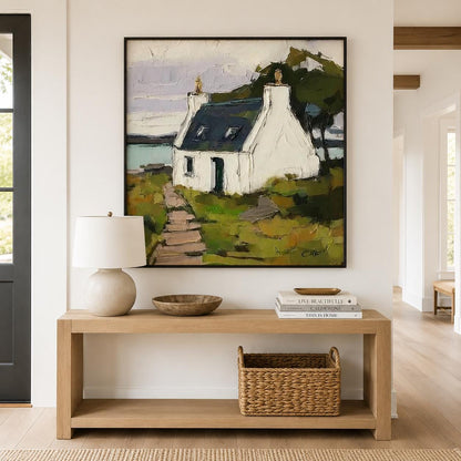 May include: A square framed oil painting depicting a white cottage with a dark blue roof situated on a grassy landscape with a path leading to the entrance. The scene includes a body of water in the background and thick, textured brushstrokes.
