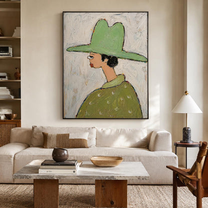 May include: A framed wall art piece featuring a stylized painting of a figure in profile wearing a wide-brimmed light green hat and a matching green shirt with white accents, set against a textured, off-white, and light gray painted background.