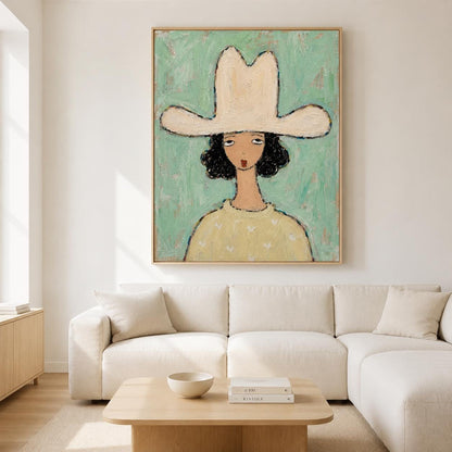 May include: A framed painting featuring a stylized portrait of a person with dark hair wearing a large, cream-colored cowboy hat. The figure wears a pale yellow sweater against a textured, light mint green background with visible brushstrokes.