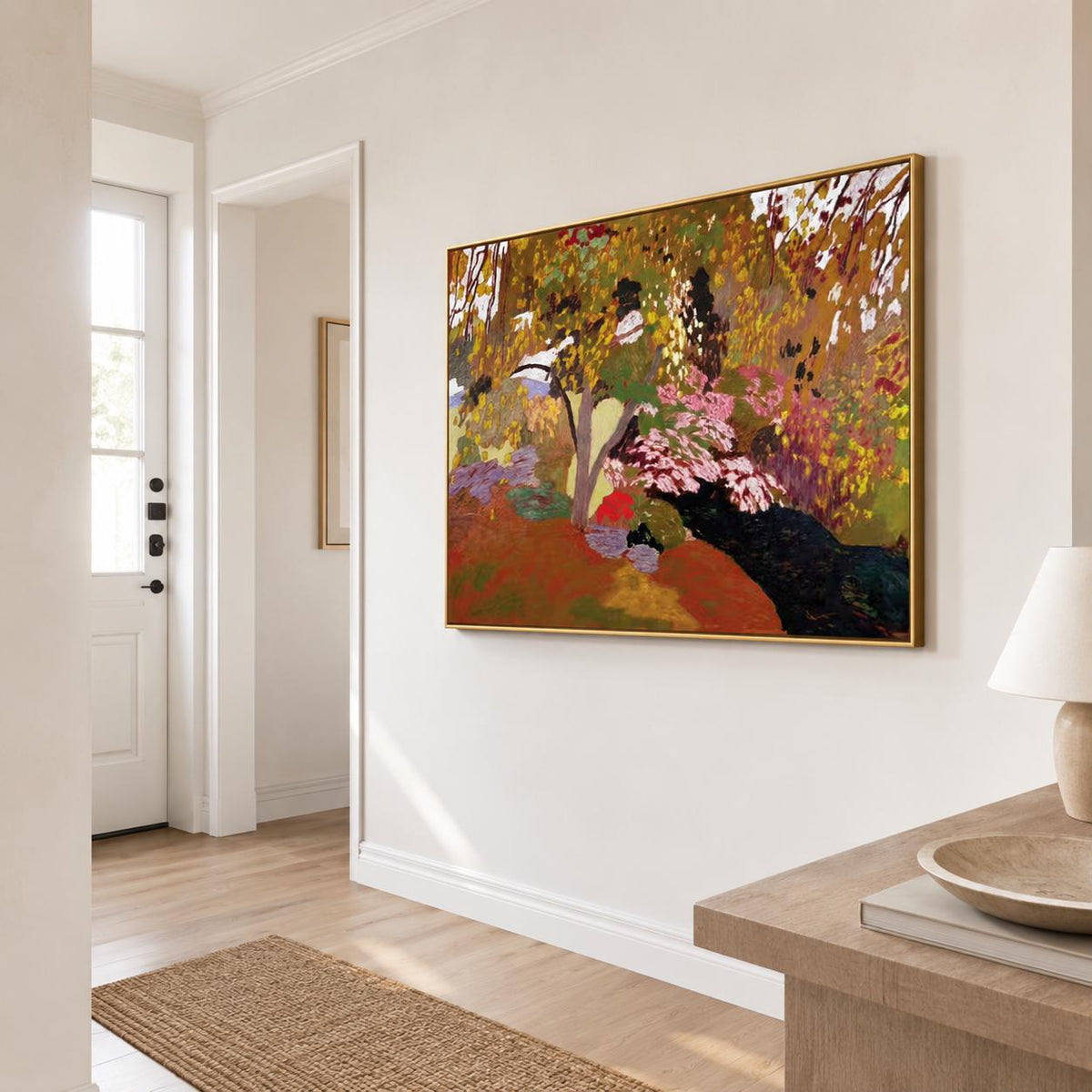 May include: A rectangular landscape painting in a gold frame featuring an abstract forest scene with a palette of deep red, earthy brown, vibrant yellow, and soft pink tones, displayed on a plain white wall in a bright, neutral-toned hallway.