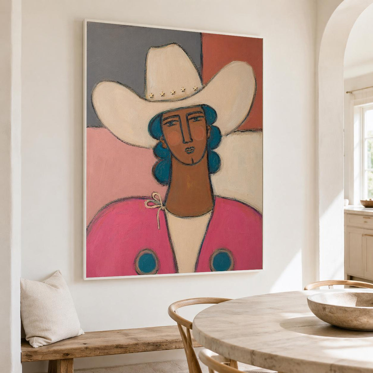 May include: A framed painting depicting a person wearing a wide-brimmed cream cowboy hat with small star accents. The figure has blue hair, a tan complexion, and wears a bright pink garment with two blue circular details on the chest area.