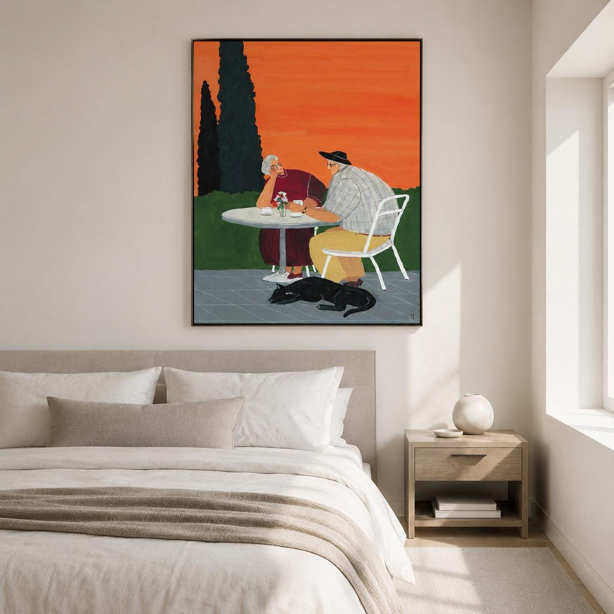 May include: A framed wall art print depicting two people sitting at a round white table outdoors against a vibrant orange sky. One person wears a dark red garment, the other a plaid shirt and yellow trousers. A black cat rests on the gray patio floor.