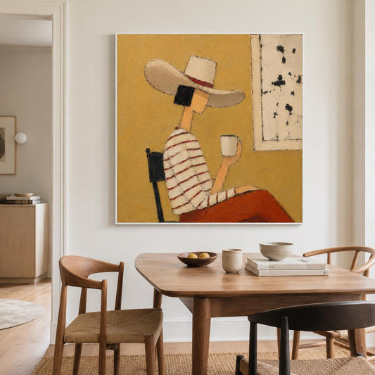 May include: A square wall art print featuring a stylized painting of a person wearing a wide-brimmed hat and a striped long-sleeve shirt, sitting on a chair while holding a white mug against a solid mustard yellow background with a white panel.