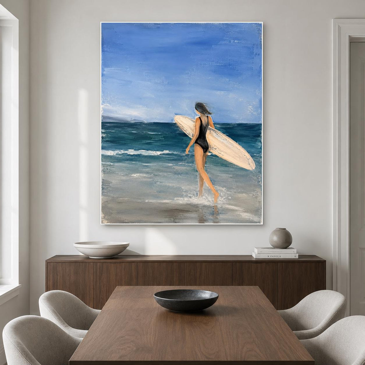 May include: An oil painting on canvas depicting a person in a black swimsuit walking into the ocean while carrying a light-colored surfboard. The scene features a deep blue sky, dark teal waves, and light gray sand at the water's edge.