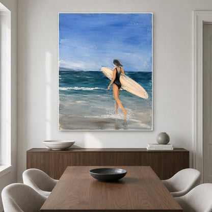 May include: An oil painting on canvas depicting a person in a black swimsuit walking into the ocean while carrying a light-colored surfboard. The scene features a deep blue sky, dark teal waves, and light gray sand at the water's edge.