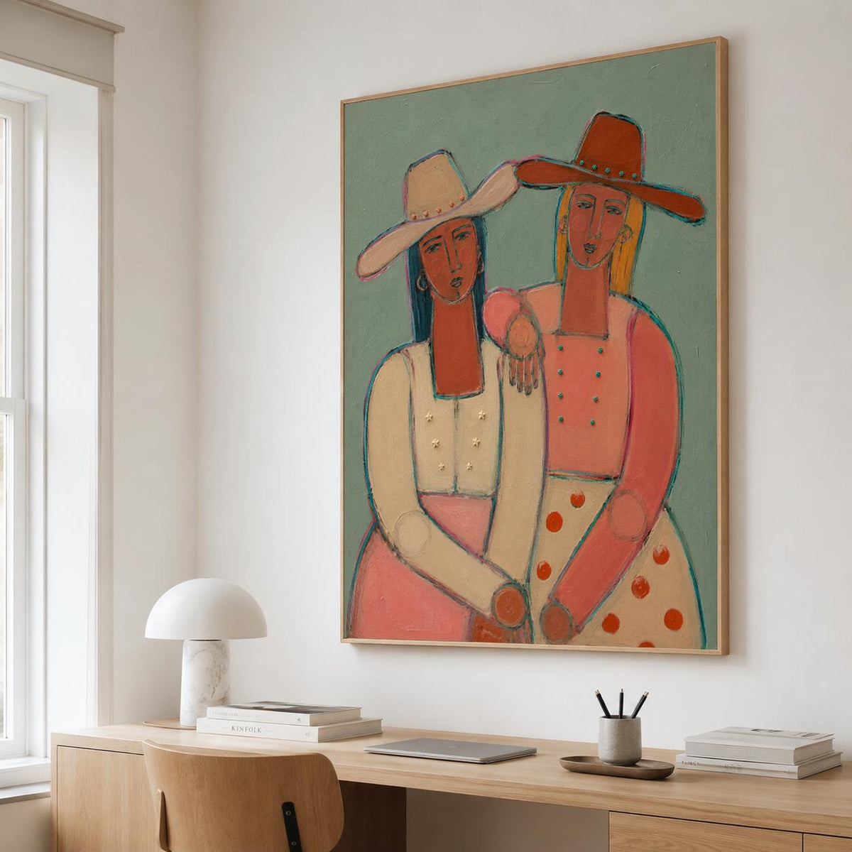 May include: A framed wall art print featuring a stylized painting of two figures wearing wide-brimmed hats. The figure on the left wears a cream top and pink skirt, while the figure on the right wears a coral top and a white skirt with orange dots.