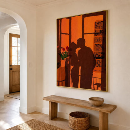 May include: A large rectangular wall art piece in a gold frame featuring a dark brown silhouette of two people kissing against a vibrant orange background. The artwork includes a small vase with red flowers and a vertical panel with black sketches.