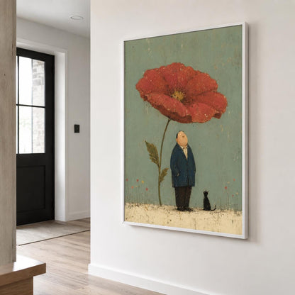 May include: A framed wall art print featuring a large red poppy flower on a muted green background. Below the flower stands a person in a dark blue suit and a small black cat, both looking up toward the bloom. The scene is set on a textured beige ground.