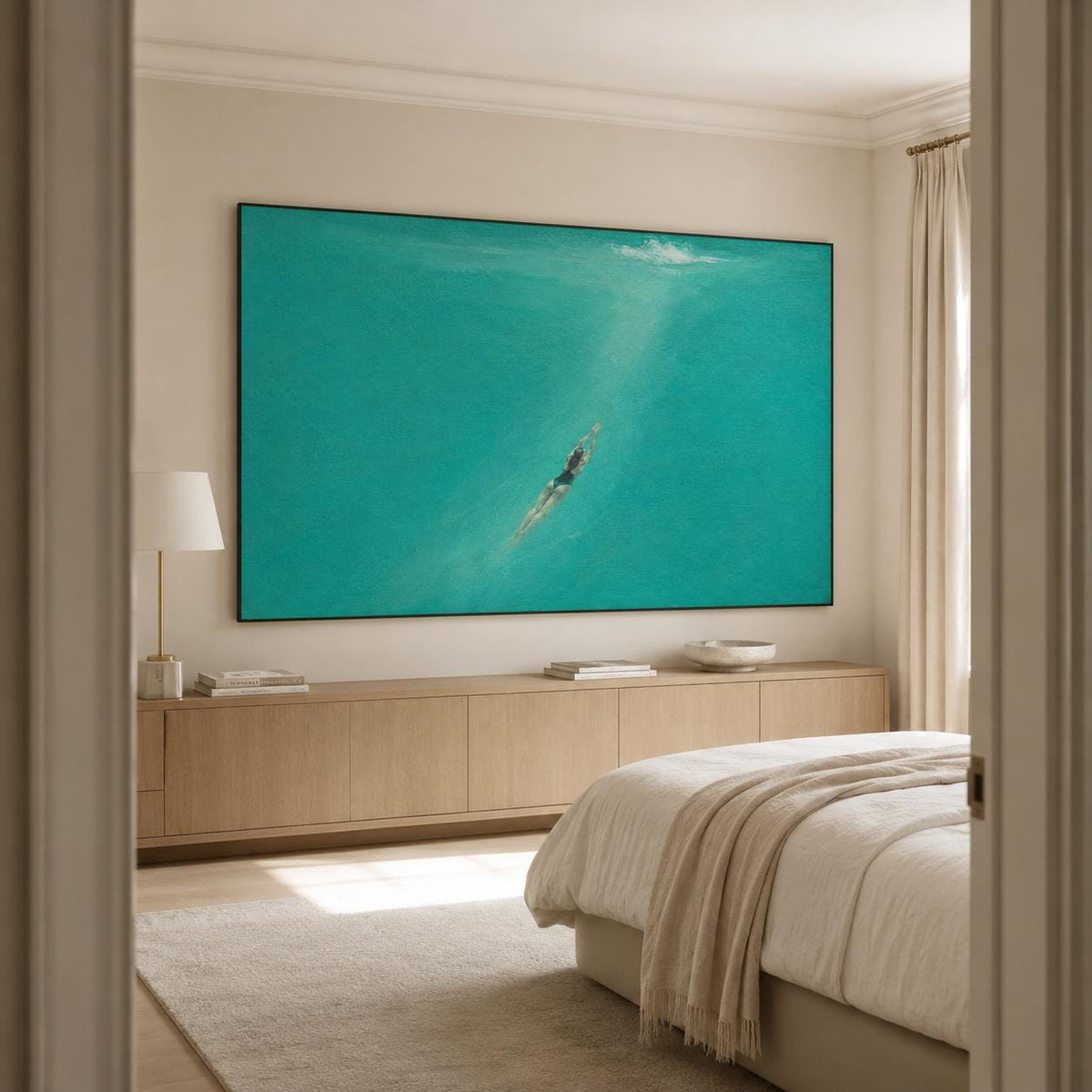 May include: A large rectangular wall art piece featuring a swimmer submerged in vibrant turquoise water. The artwork is framed in a thin black border and is mounted on a light beige wall above a long wooden console table in a bedroom setting.
