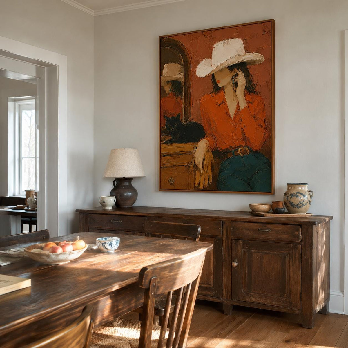May include: A rectangular framed oil painting depicting a person wearing a white cowboy hat and an orange long-sleeve shirt with blue jeans. The person is positioned near a wooden dresser with a black cat resting on top, set against a terracotta background.