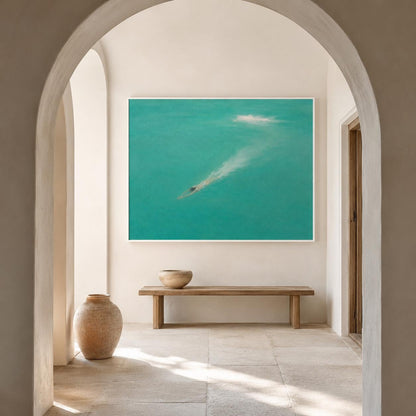 May include: A large rectangular wall art piece featuring a turquoise ocean scene with a swimmer creating a white wake, displayed above a long wooden bench and a rounded terracotta-colored floor vase in a neutral-toned arched hallway.