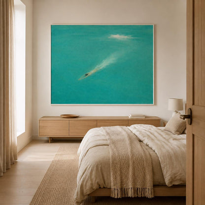 May include: A large rectangular wall art piece featuring a vibrant turquoise sea scene with a small dark figure swimming and creating a white wake. The artwork is framed in a thin white border and mounted on a plain off-white wall above a wooden console.