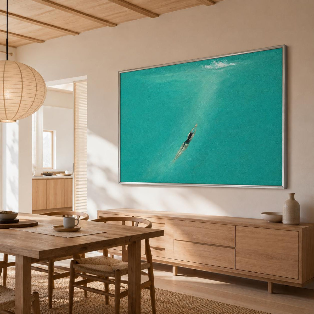 May include: A large rectangular wall art piece featuring a swimmer in dark swimwear submerged in vibrant turquoise water. The painting is framed in a thin silver metal border and is displayed on a light beige wall above a wooden sideboard.