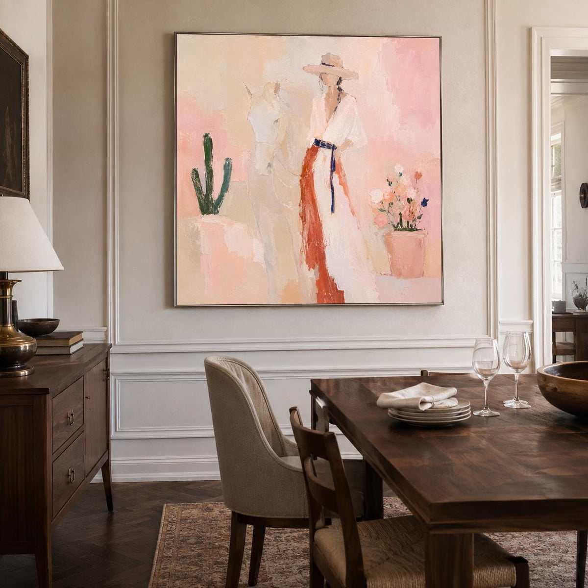 May include: A square wall painting featuring an impressionistic scene with a person in a wide-brimmed hat and a long dress, standing beside a white horse. The composition includes a green cactus and a potted plant against a soft pink background.