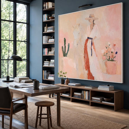 May include: A large rectangular framed painting featuring an abstract depiction of a person wearing a wide-brimmed hat and a long garment standing beside a horse, a cactus, and a potted plant, rendered in soft shades of peach, pink, and white.