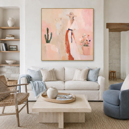 May include: A square canvas painting featuring an abstract depiction of a person wearing a wide-brimmed hat and a long dress with a dark belt, standing beside a horse and a cactus, rendered in soft shades of peach, pink, and terracotta.